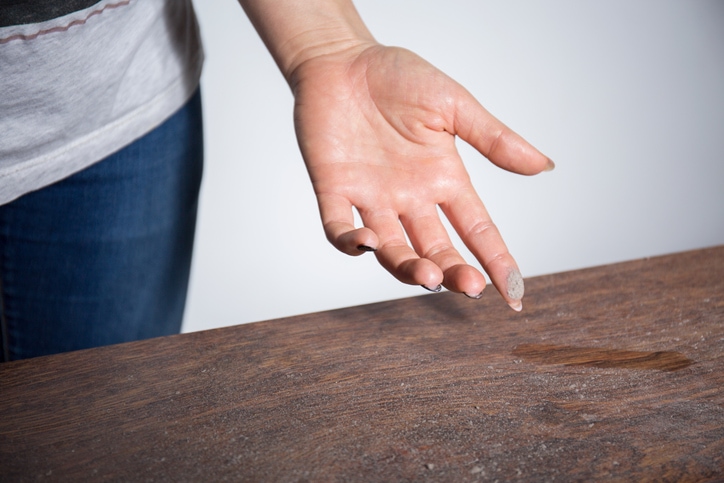 dust on a table inside a woman's home showing the possible difference between a air filter and an air cleaner