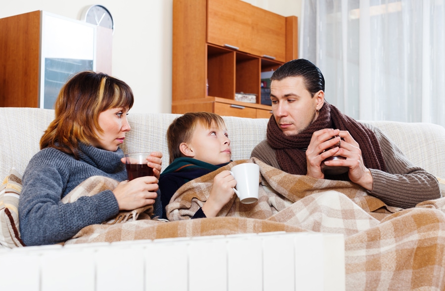 Family trying to stay warm under blankets and trying to determine why their furnace isn't heating their entire home.