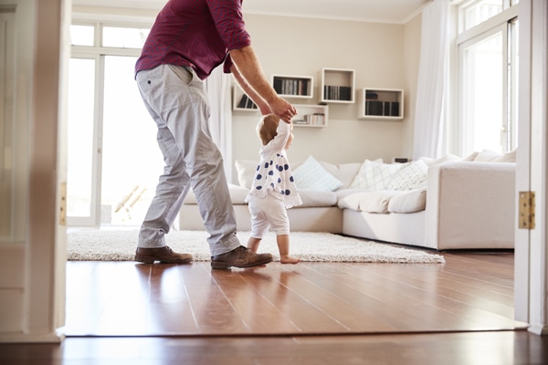 Father helping daughter to walk in healthy indoor air quality at home after learning how UV lights benefit their HVAC system.