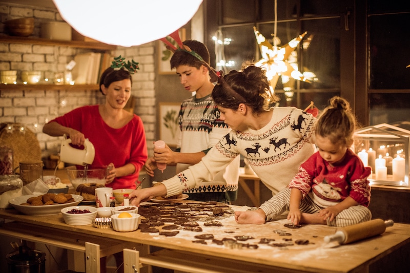 Mother with children in kitchen preparing Christmas cakes