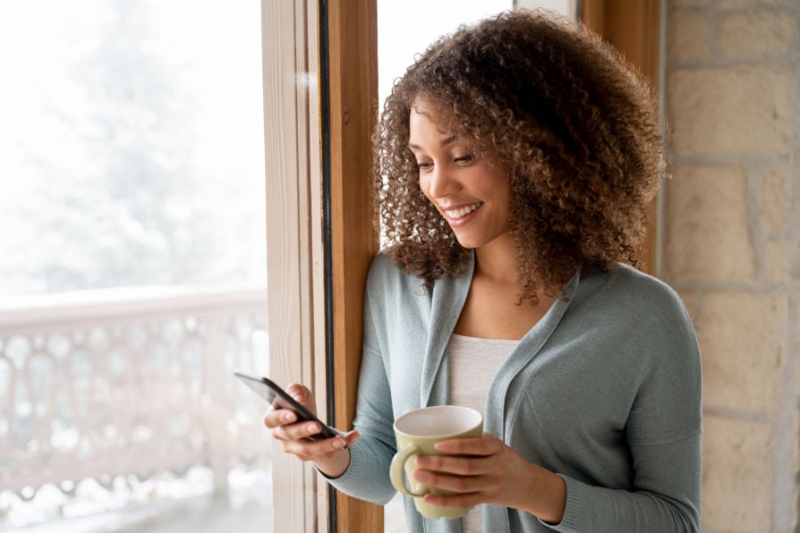 Woman researching on her phone how to make her furnace last longer in her home.