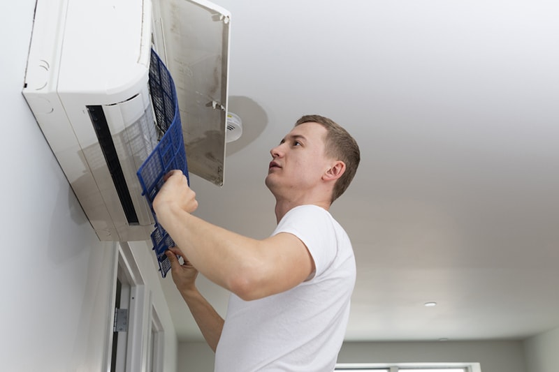 The young man cleaning filters in the air-conditioning split device in the recently rented apartment in Brooklyn, New York, USA